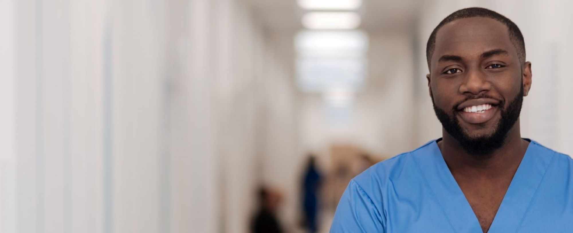 male strike nurse in blue scrubs smiling